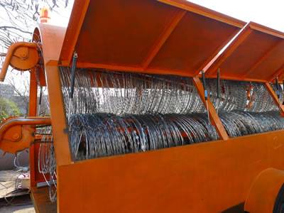 An orange deployment truck with razor wire on the ground.
