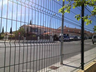 A black PVC coated welded wire 3D security fence is installed beside the road to protect passengers.