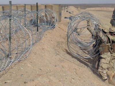 Several soldiers are arranging the concertina razor wire.