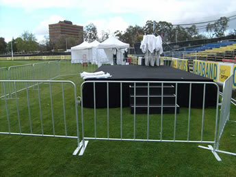 Crowd control barriers are installed on the grassland surrounding the stage.