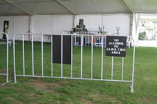 A black warning sign with the white words is fastened on the crowd control barrier.
