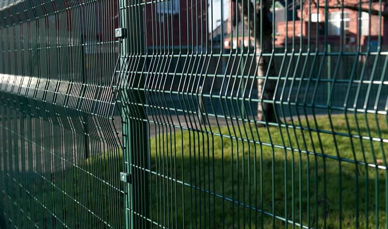 The two green PVC coated paladin fence panels are jointed together in a post, installed in a residential field.