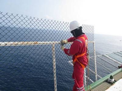 A worker is installing chain link helideck mesh.